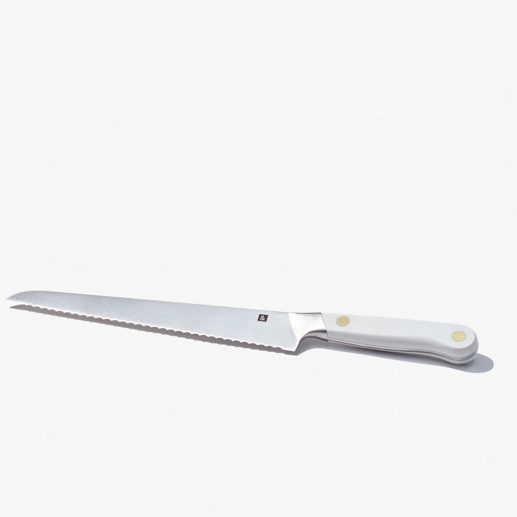 Bread knife laid flat, showing the full serrated edge and white handle