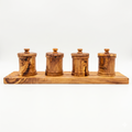 Four lidded olive wood canisters lined up on a long olive wood base against white
