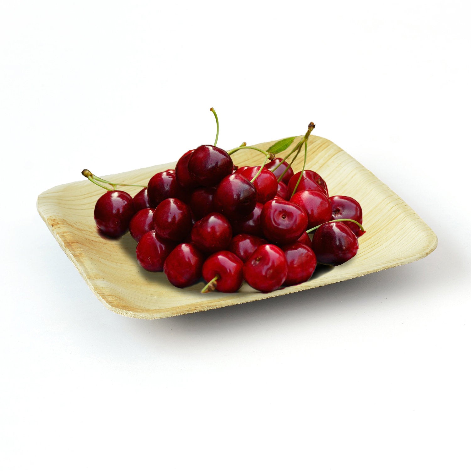 Fresh cherries piled on a square palm leaf plate