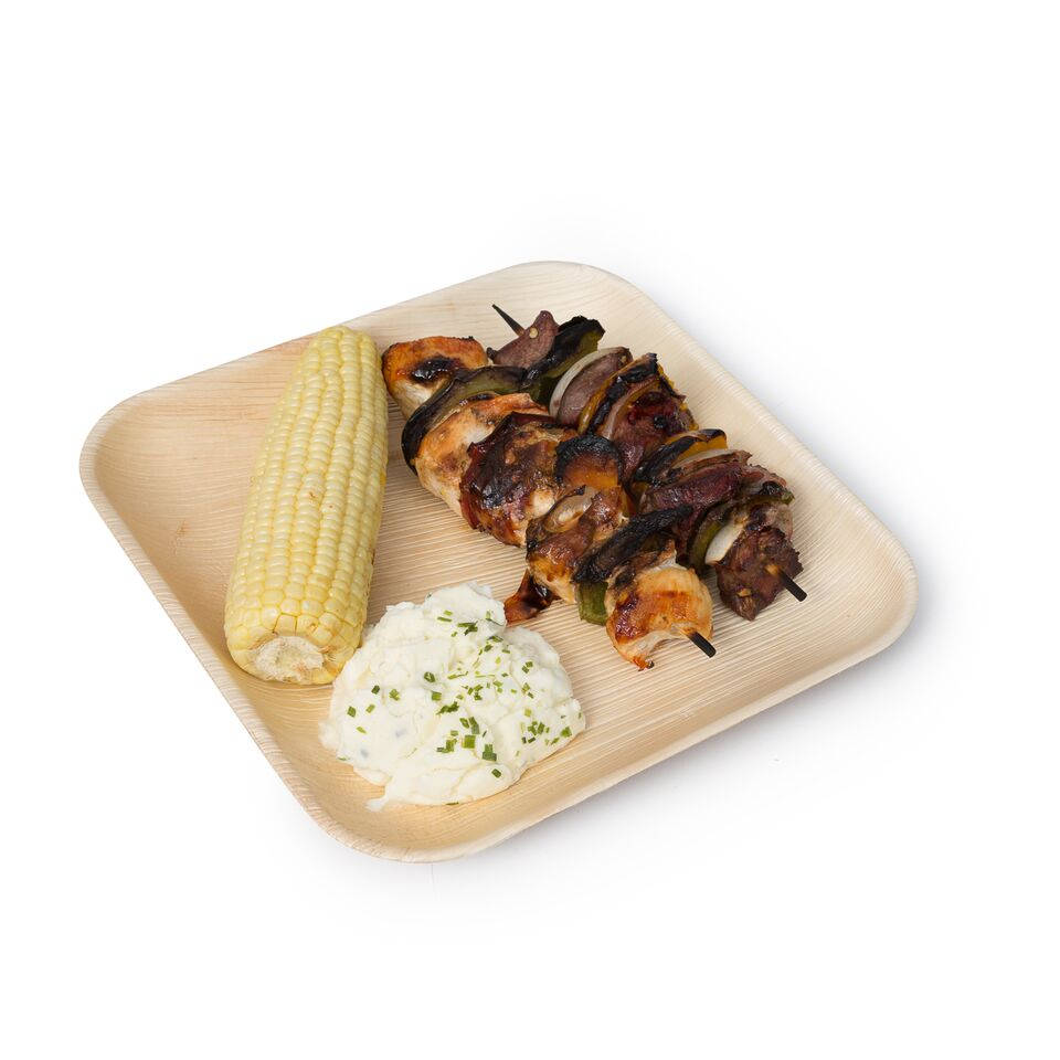 Grilled skewers, corn and rice served on a square palm leaf plate