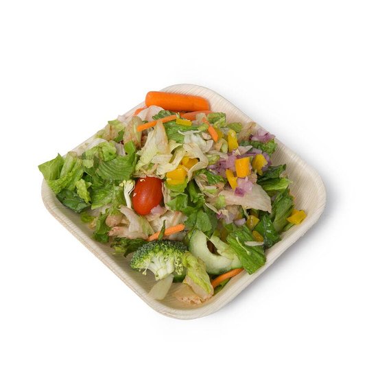 Palm leaf plate holding a mixed green salad with carrots and tomatoes