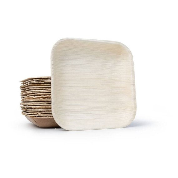 Square areca palm leaf plate propped against a stack of the same plates