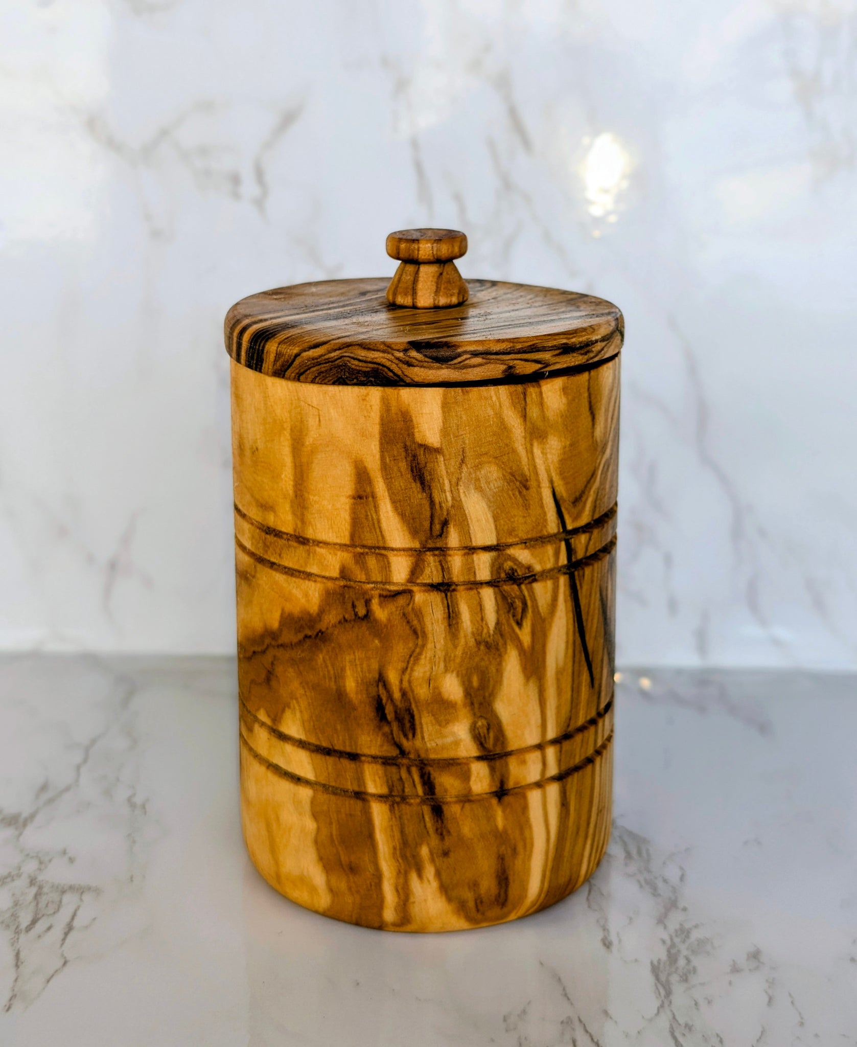 Olive wood canister with a fitted lid on a marble counter