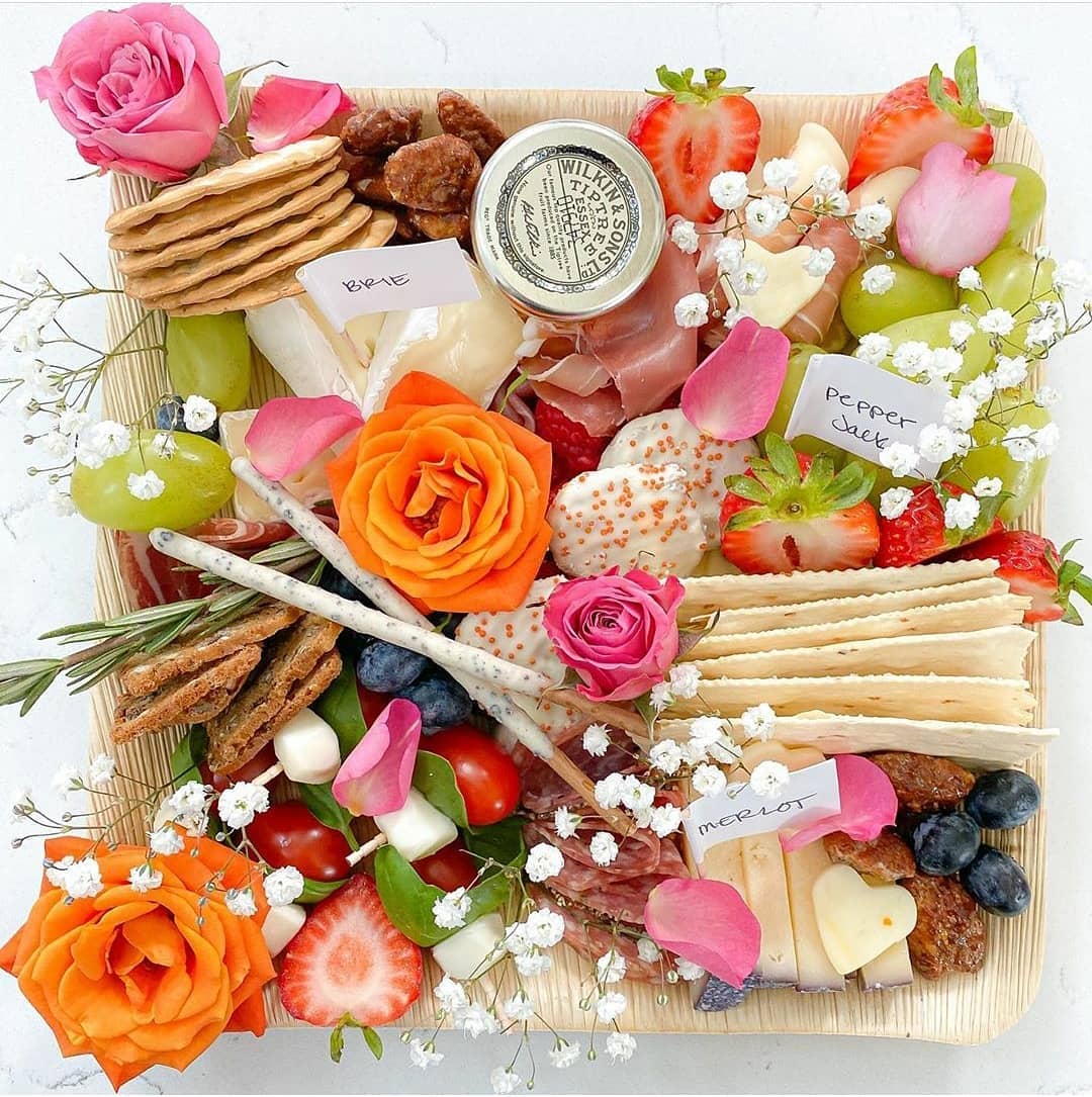 Palm leaf grazing platter with cheese, fruit, crackers and fresh roses