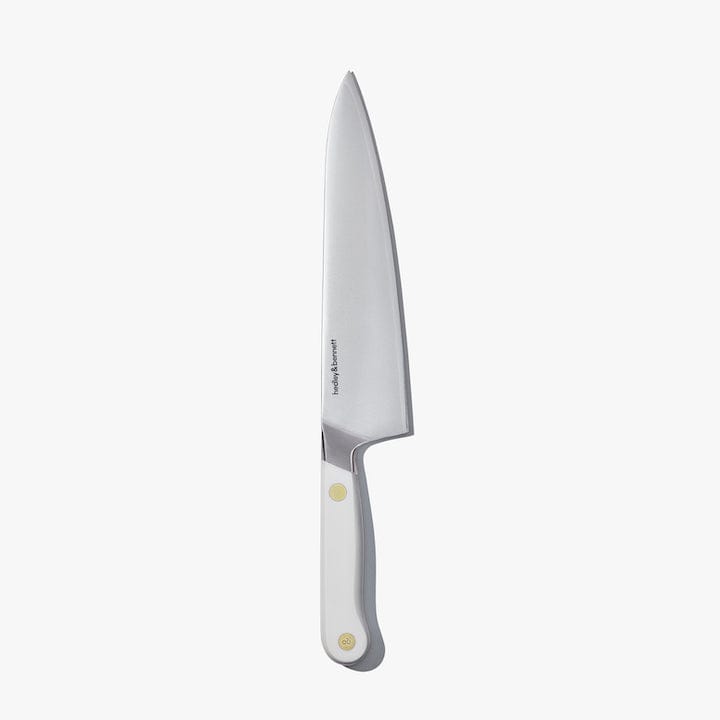 Chef's knife with a white handle and brass pin, standing upright