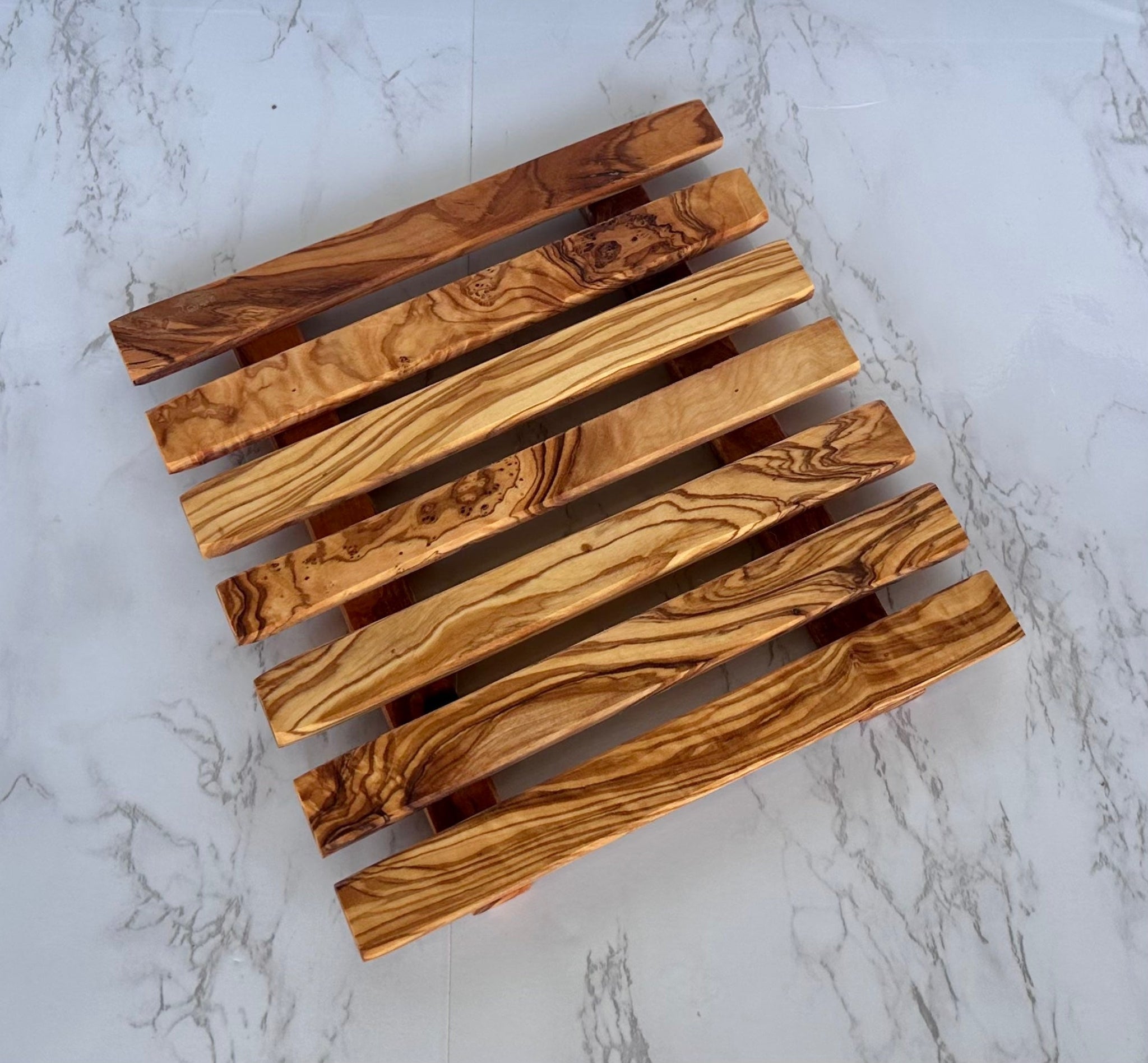 Slatted olive wood trivet on a marble surface