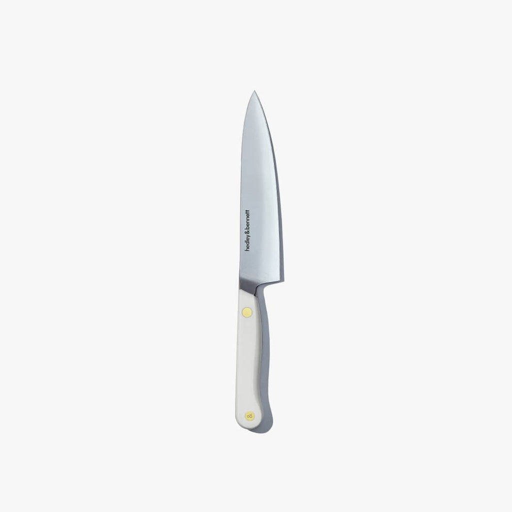 Utility knife with a white handle and brass pin, standing upright