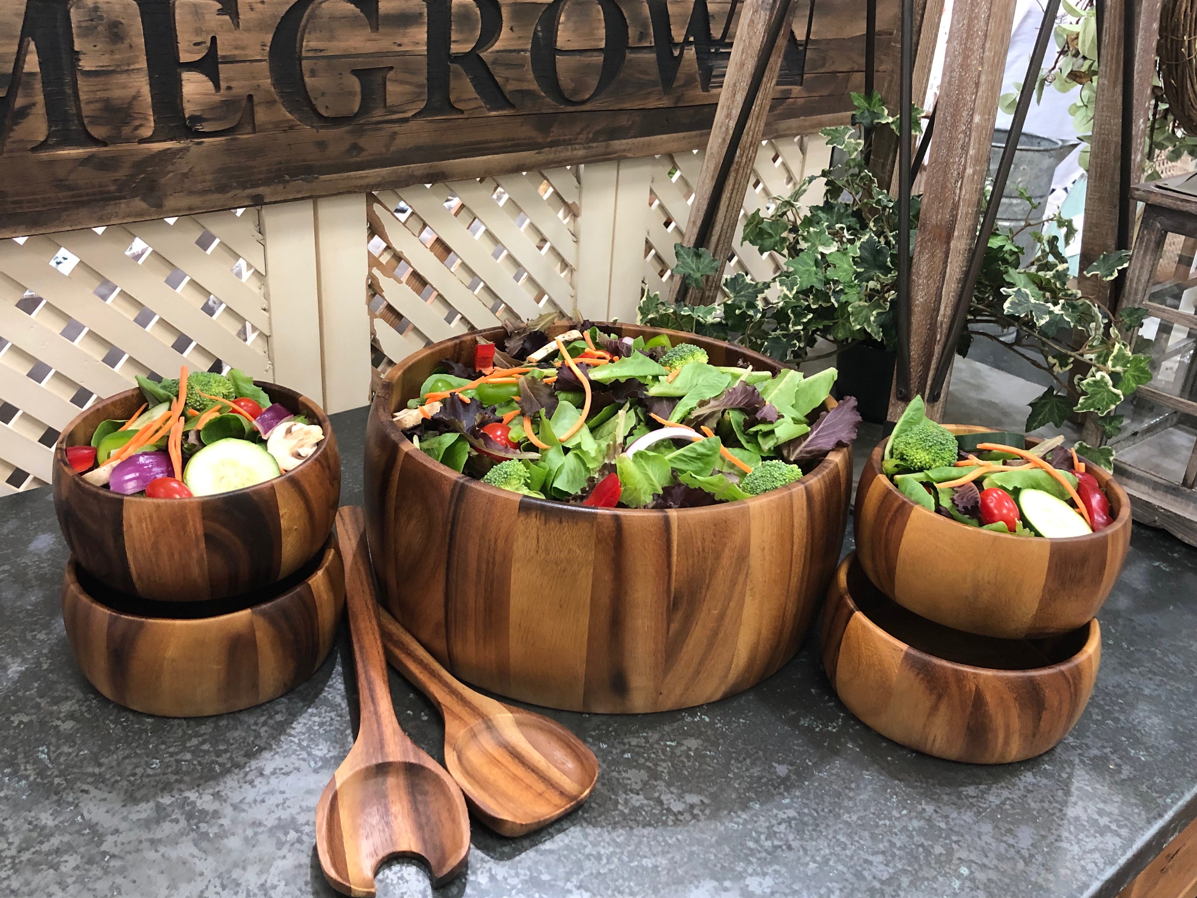 The acacia salad set filled with mixed greens, shown on a display table